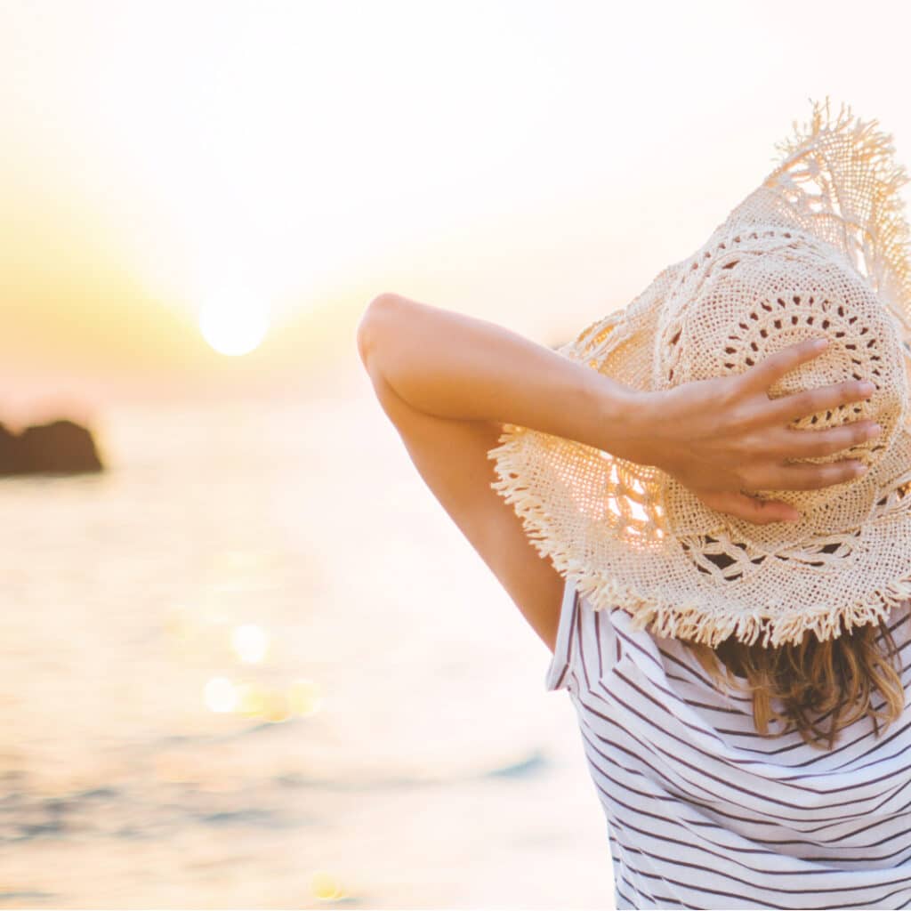 Une femme les bras grand ouvert face au soleil